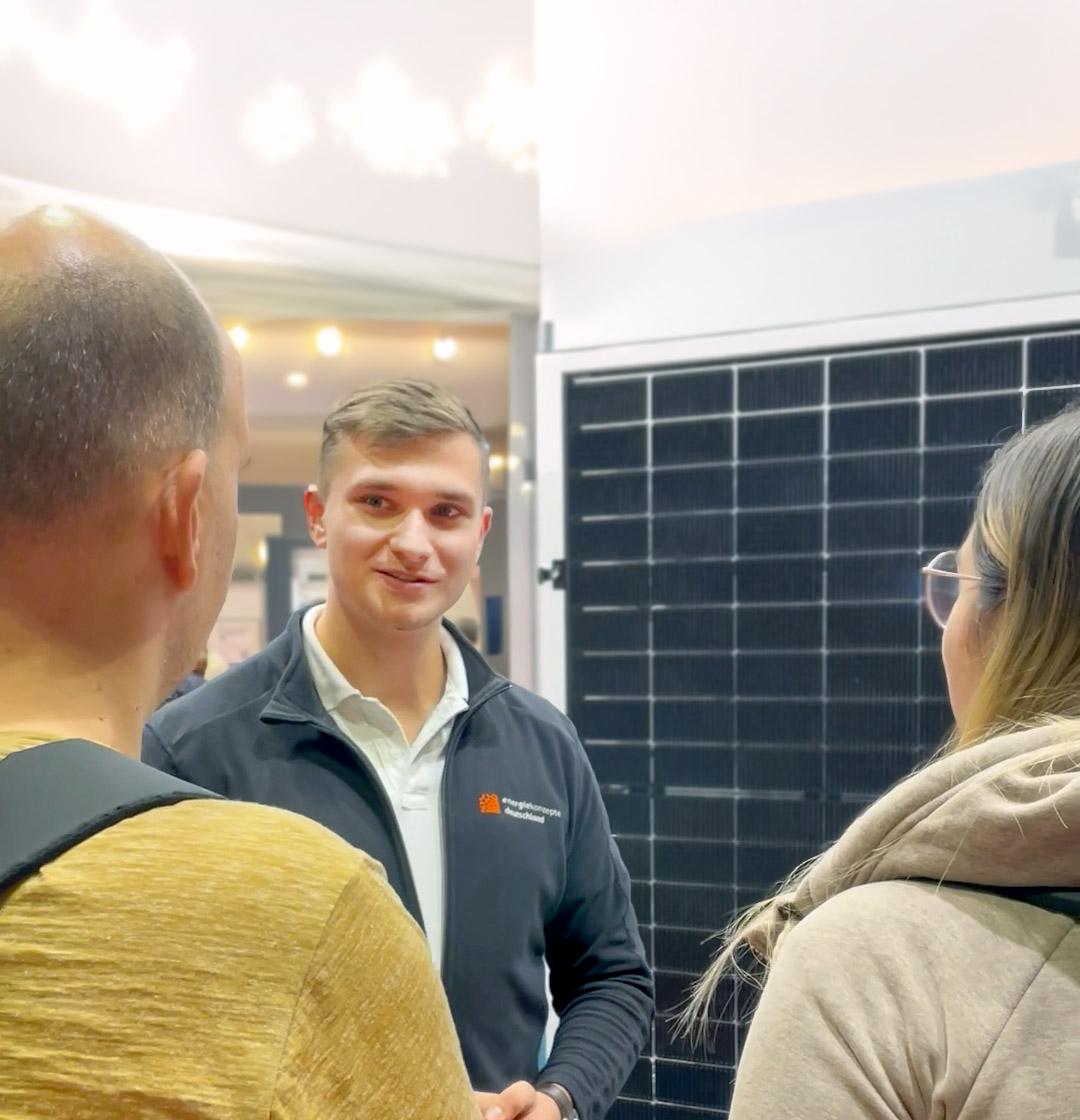 Ein Berater von EKD mit 2 Kunden vor einer Solaranlage im Gespräch