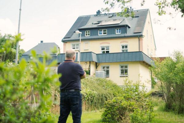 Haus mit Solaranlage auf Dach, Blick aus Garten auf Haus