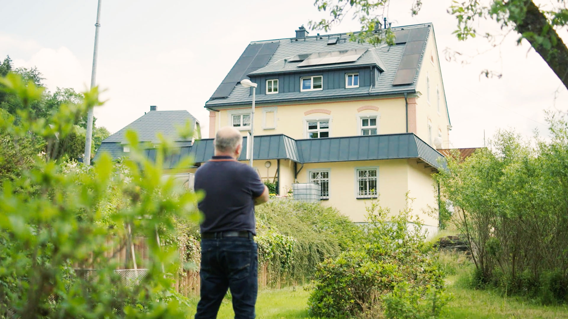 Haus mit Solaranlage auf Dach, Blick aus Garten auf Haus