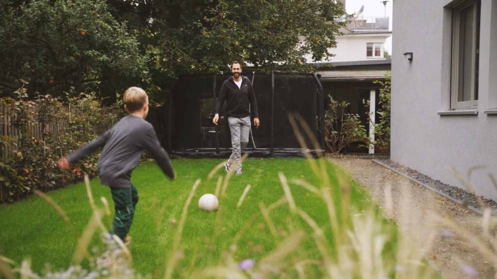 Kunde Matthias spielt Fußball im Garten mit Kind